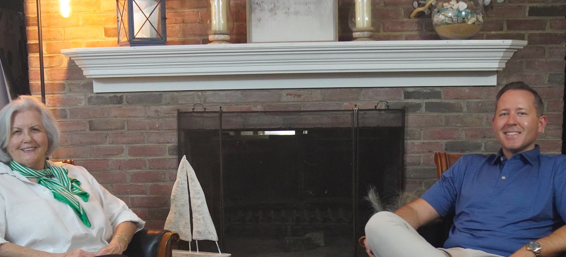 Janice Powell seated on the left and Cody Powell seated on the right in front of a fireplace